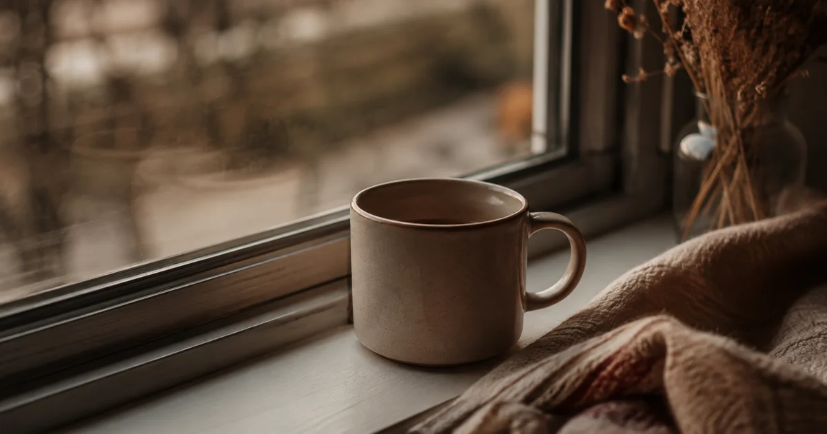 A cup of tea gone cold on a windowsill in fading afternoon light