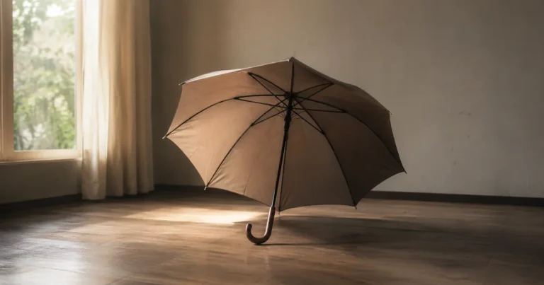 A single umbrella left open indoors on a dry floor in soft window light