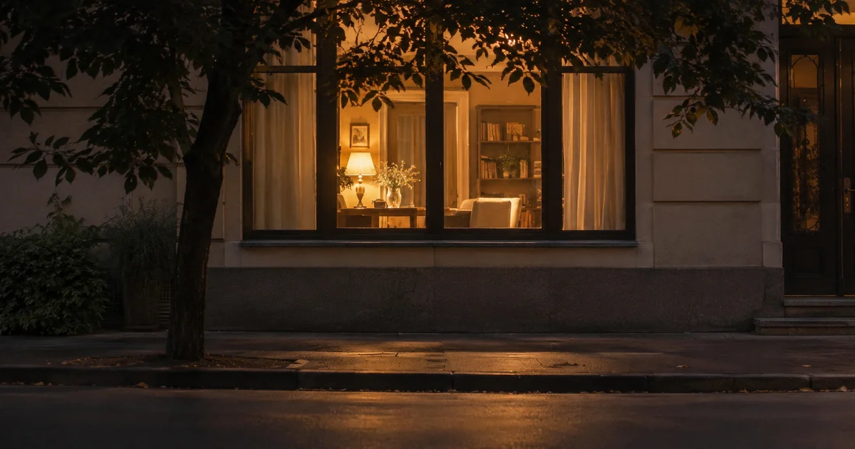 Lit window seen from across a quiet empty street at dusk