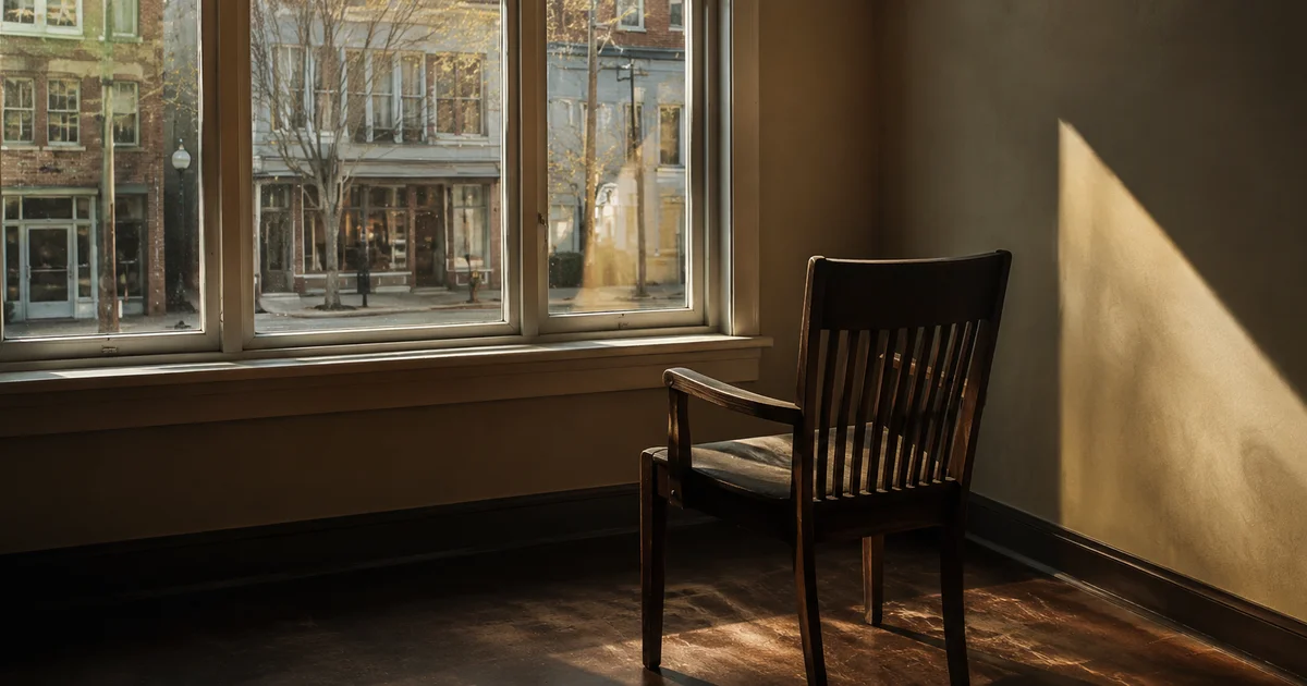 Single chair turned away from a window overlooking a quiet street