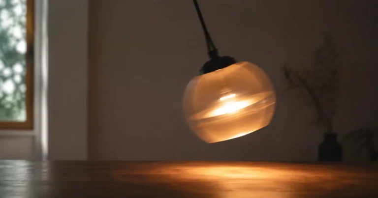 Pendulum light fixture mid-swing above a table, alternating shadow and warm glow