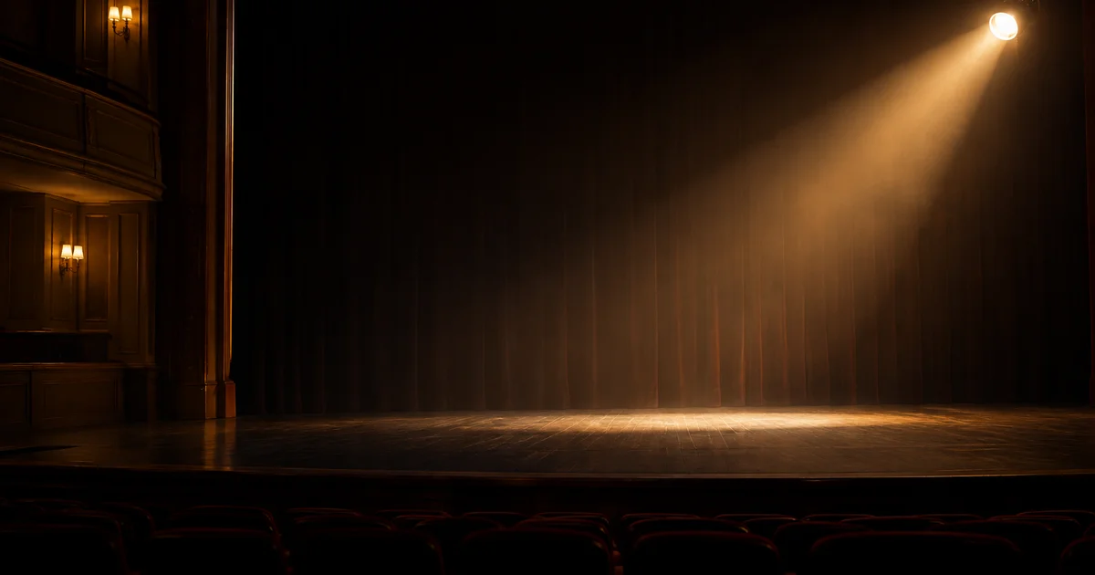 A single spotlight left on over an empty stage, no performer present, soft dim house lights