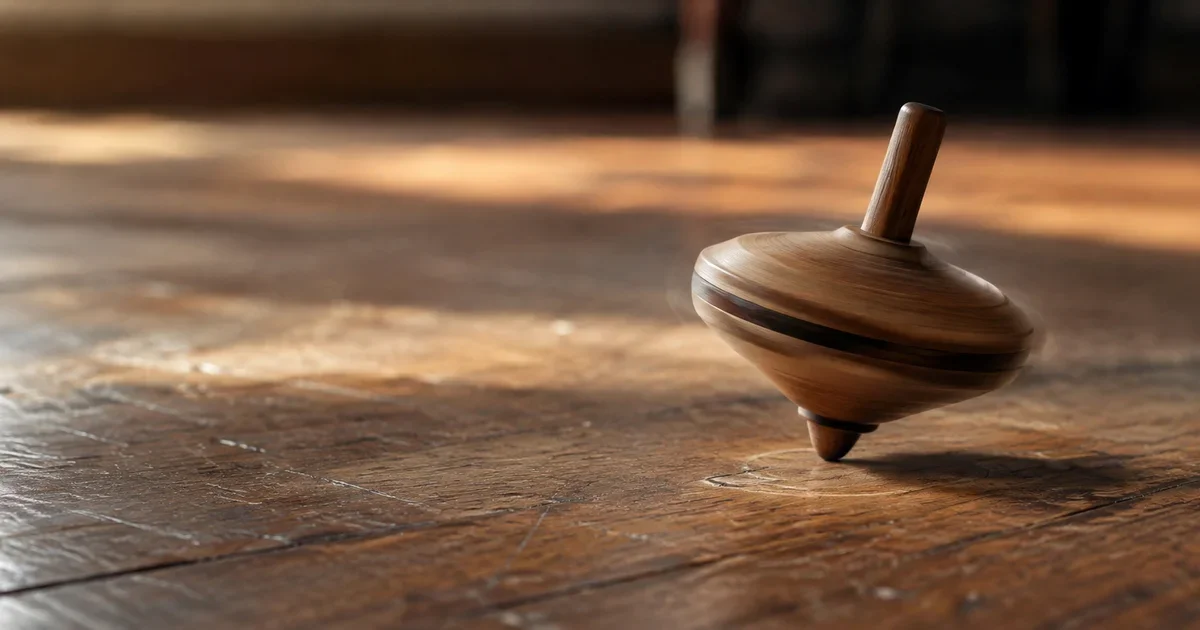 A wooden spinning top slowing while circling the same spot on a worn wooden floor