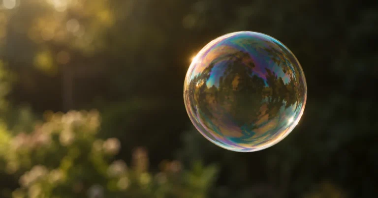 A single iridescent soap bubble floating in soft light against a dark, out-of-focus background.