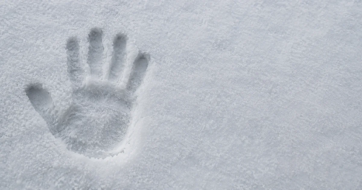 A single handprint pressed into fresh snow beside a smooth, untouched expanse